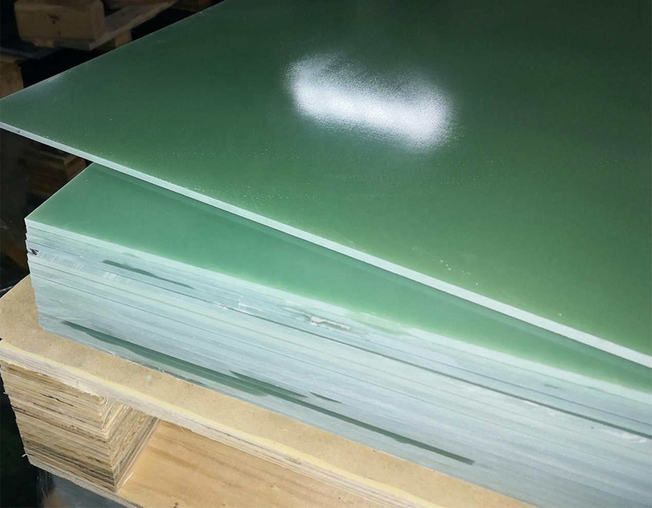 High-quality green epoxy fiberglass laminate sheets stacked on a wooden pallet for industrial use.